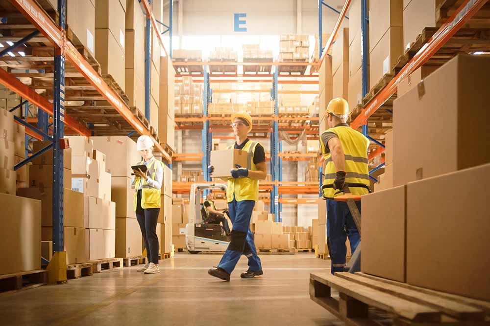 Retail Warehouse full of Shelves with Goods in Cardboard Boxes, Workers Scan and Sort Packages, Move Inventory with Pallet Trucks and Forklifts. Product Distribution Logistics Center.