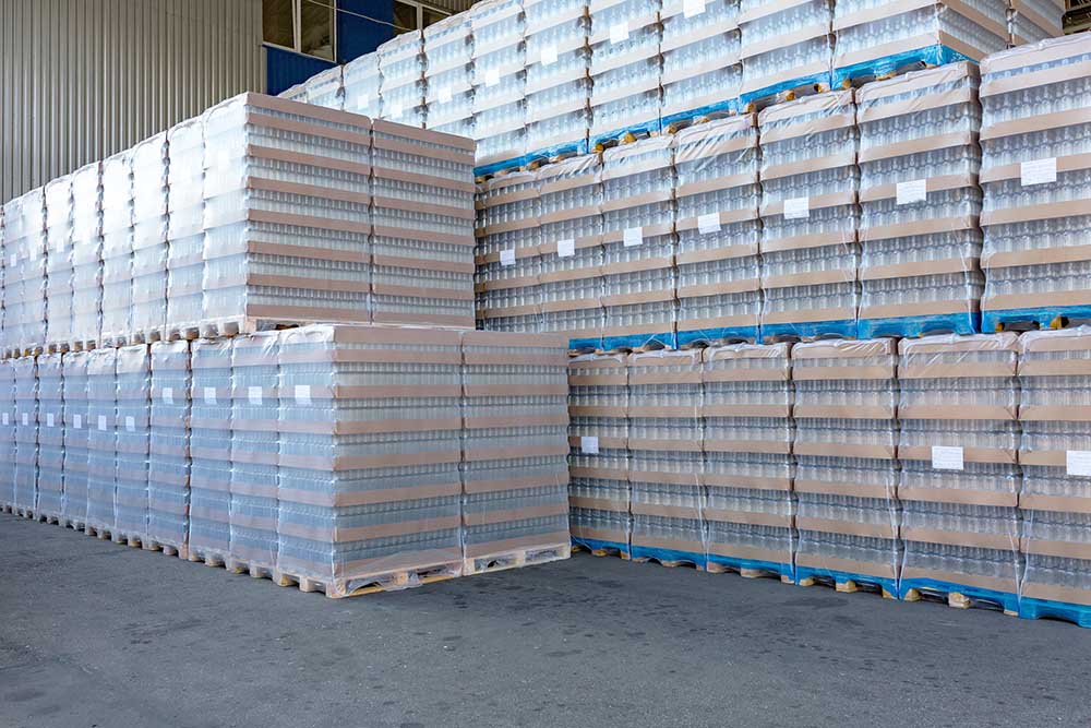 The open air storage and carriage of the finished product at industrial facility. A glass clear bottles for alcoholic or soft drinks beverages and canning jars stacked on pallets for forklift.