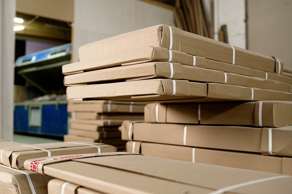 Stacks of cardboard boxes containing furniture parts sit in a warehouse, ready for shipping and delivery