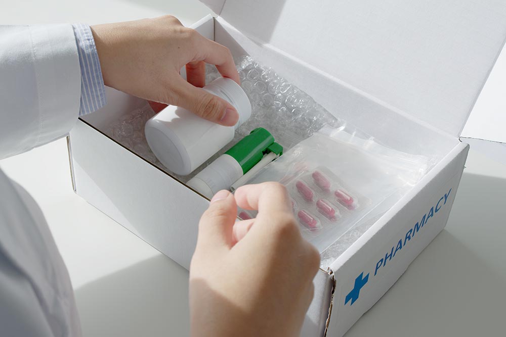 a woman placing medication in a cardboard box